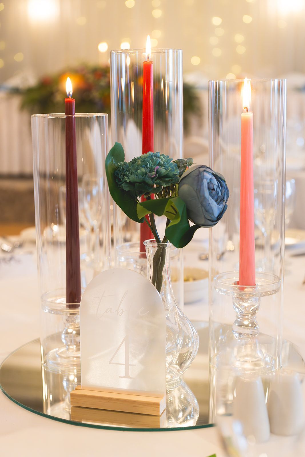 Elegant floral table centerpiece with a white rose and candles in glass holders