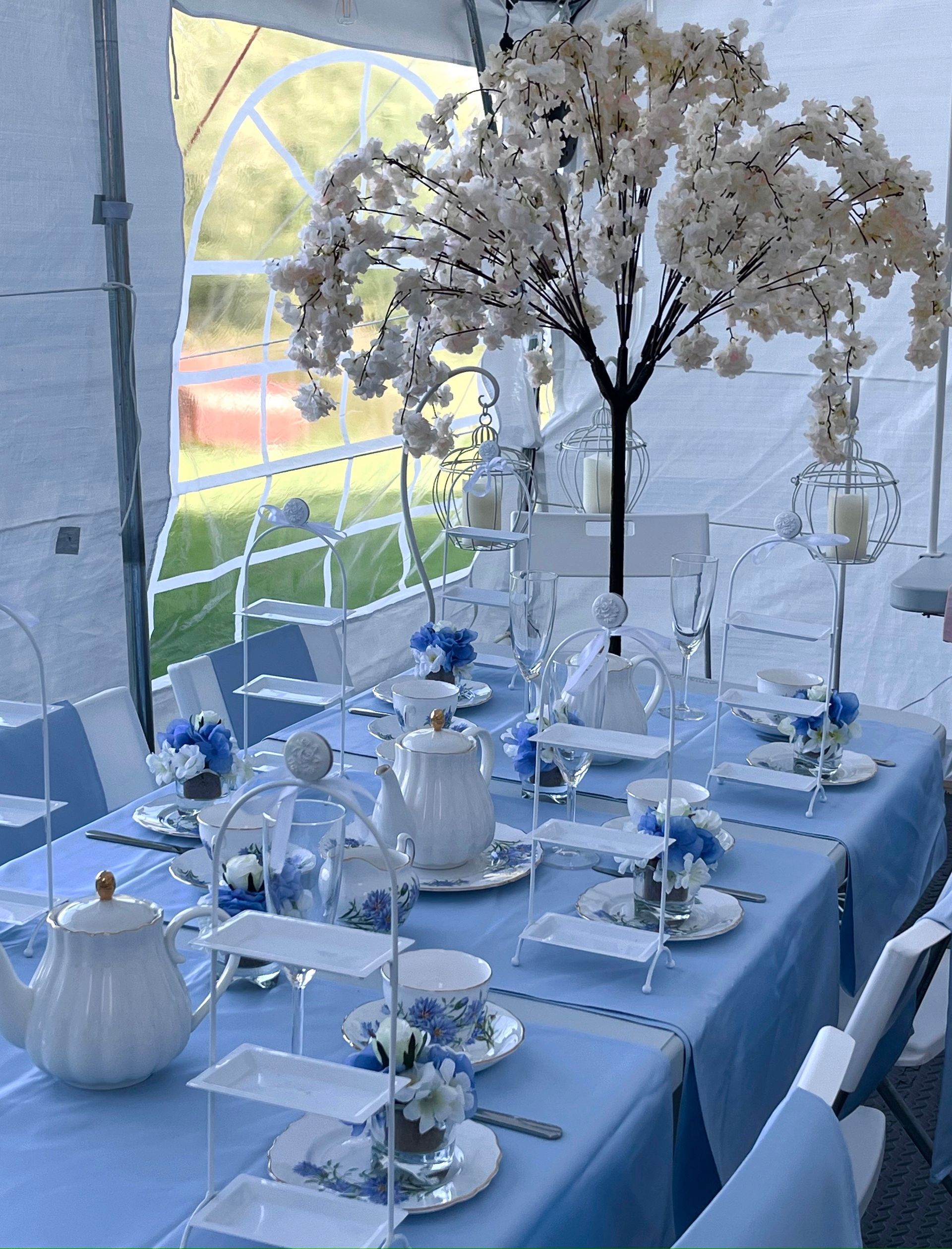 Elegant blue-and-white table setting with white flowers in a bright event tent