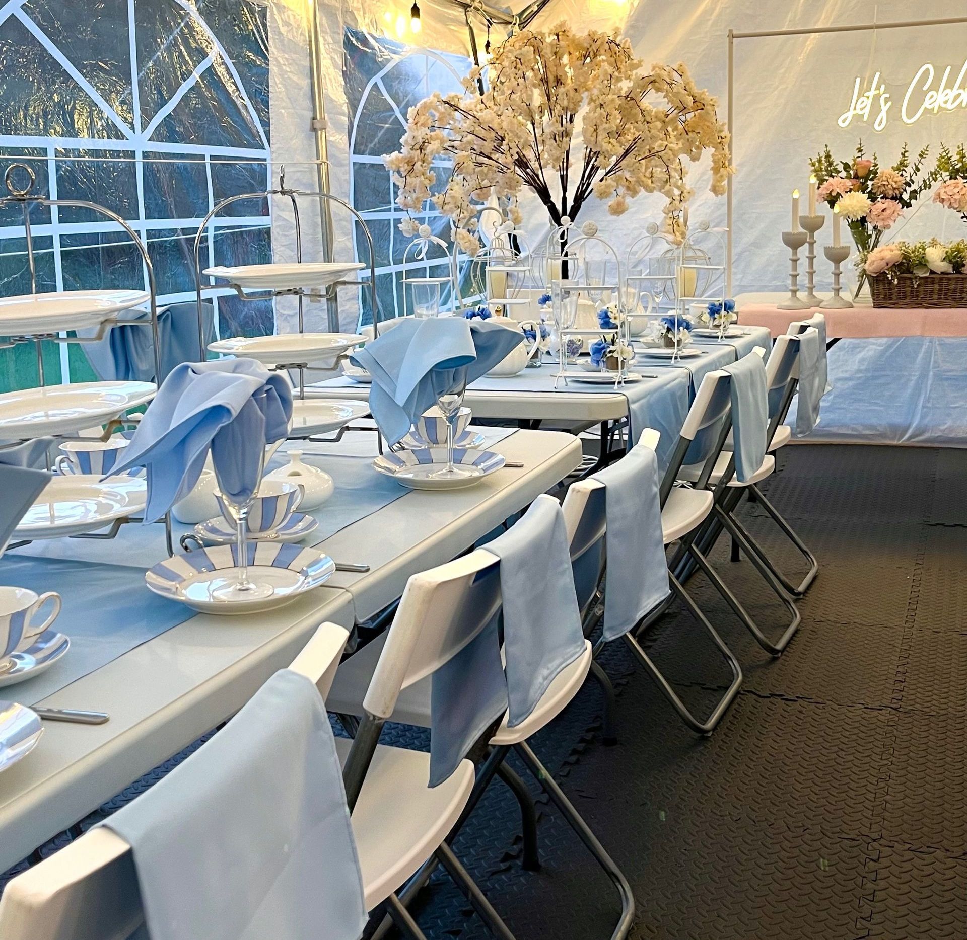 Elegant white-and-blue banquet tables set in a bright tent for a formal event