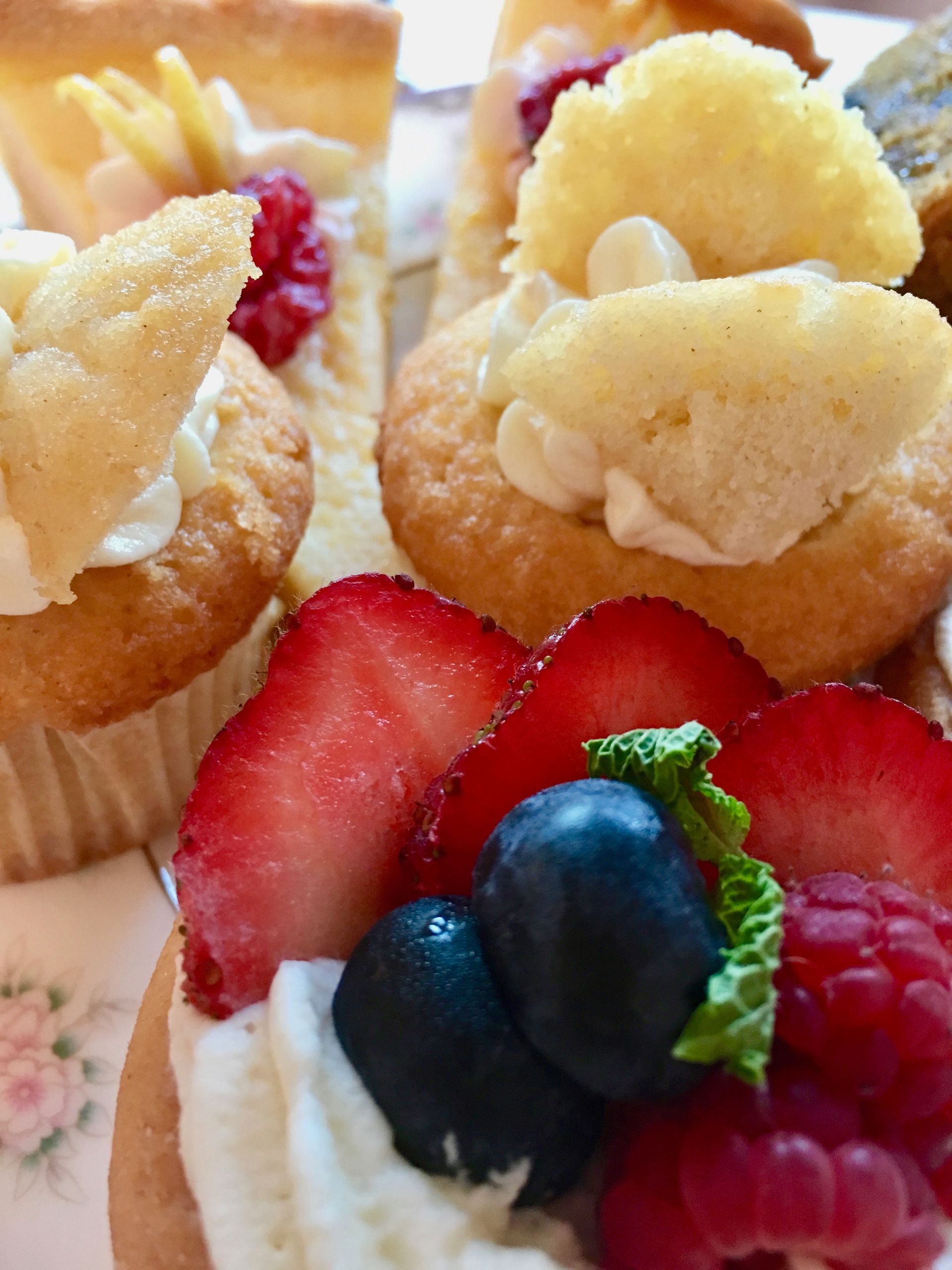Fruit-topped cream puffs with strawberries, blueberries, and raspberries on a floral tray.
