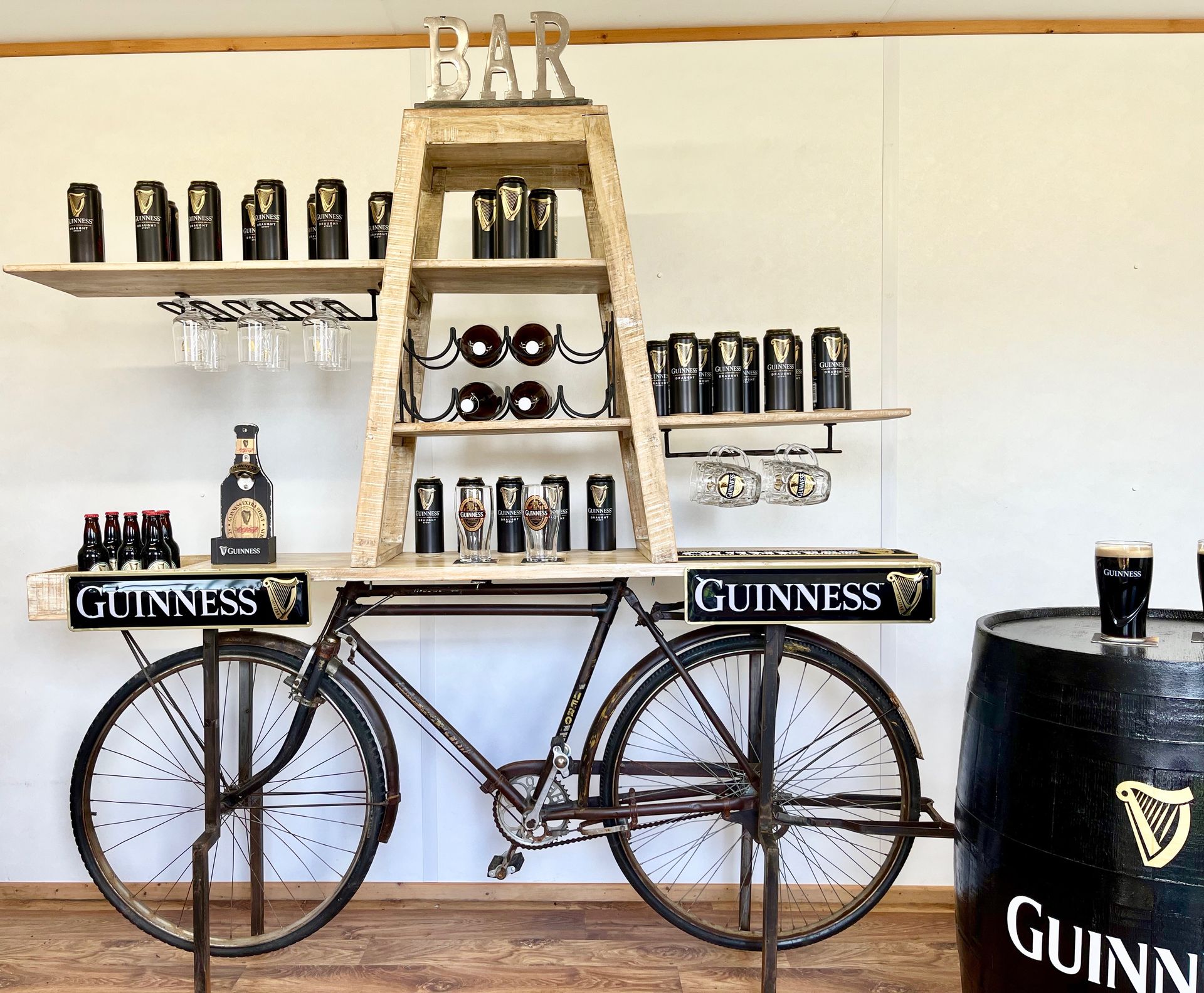Guinness-themed bar display with a bicycle cart and shelves of black Guinness cans and glasses