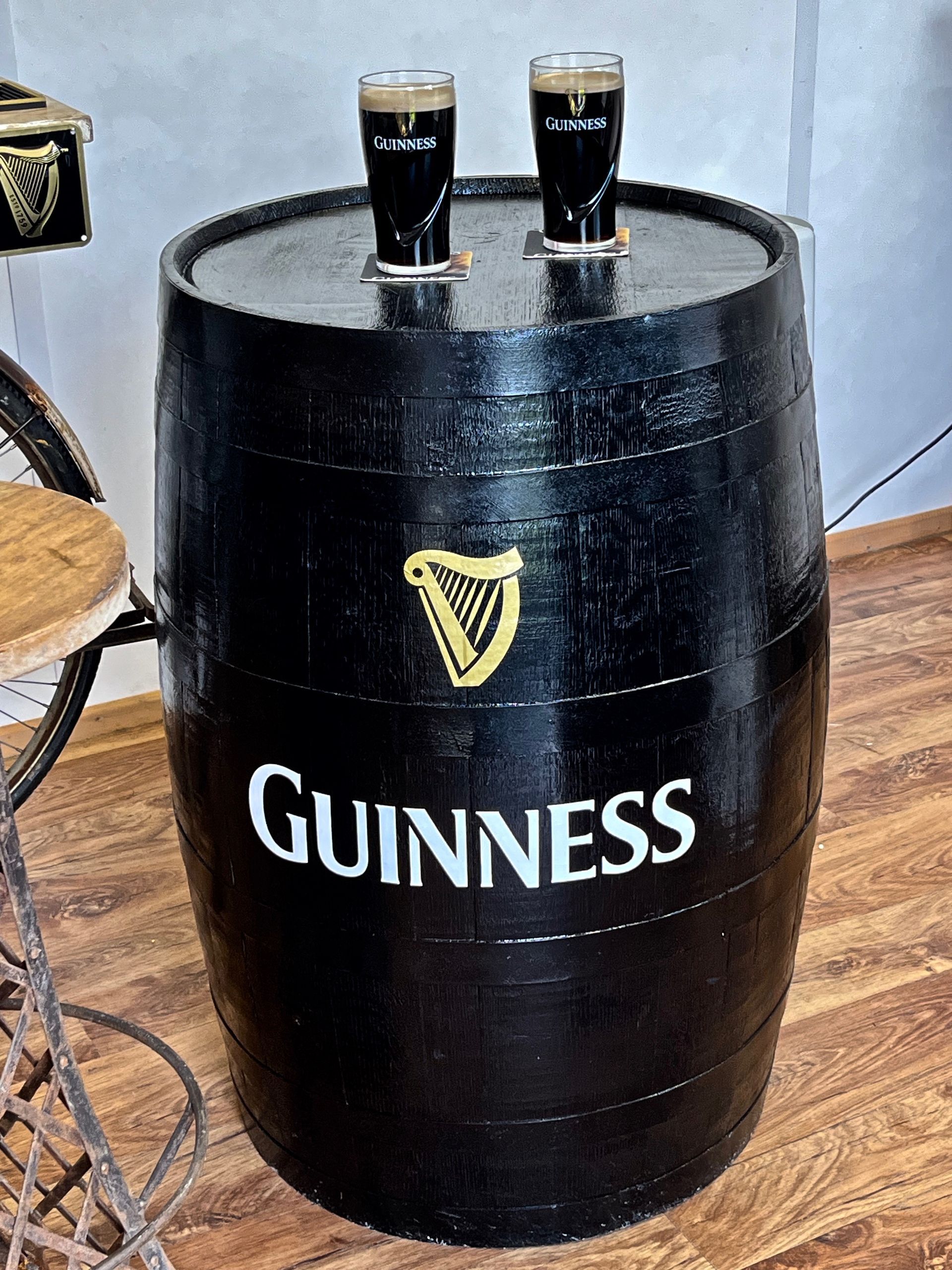 Black Guinness beer barrel table with two pint glasses on top in a pub setting