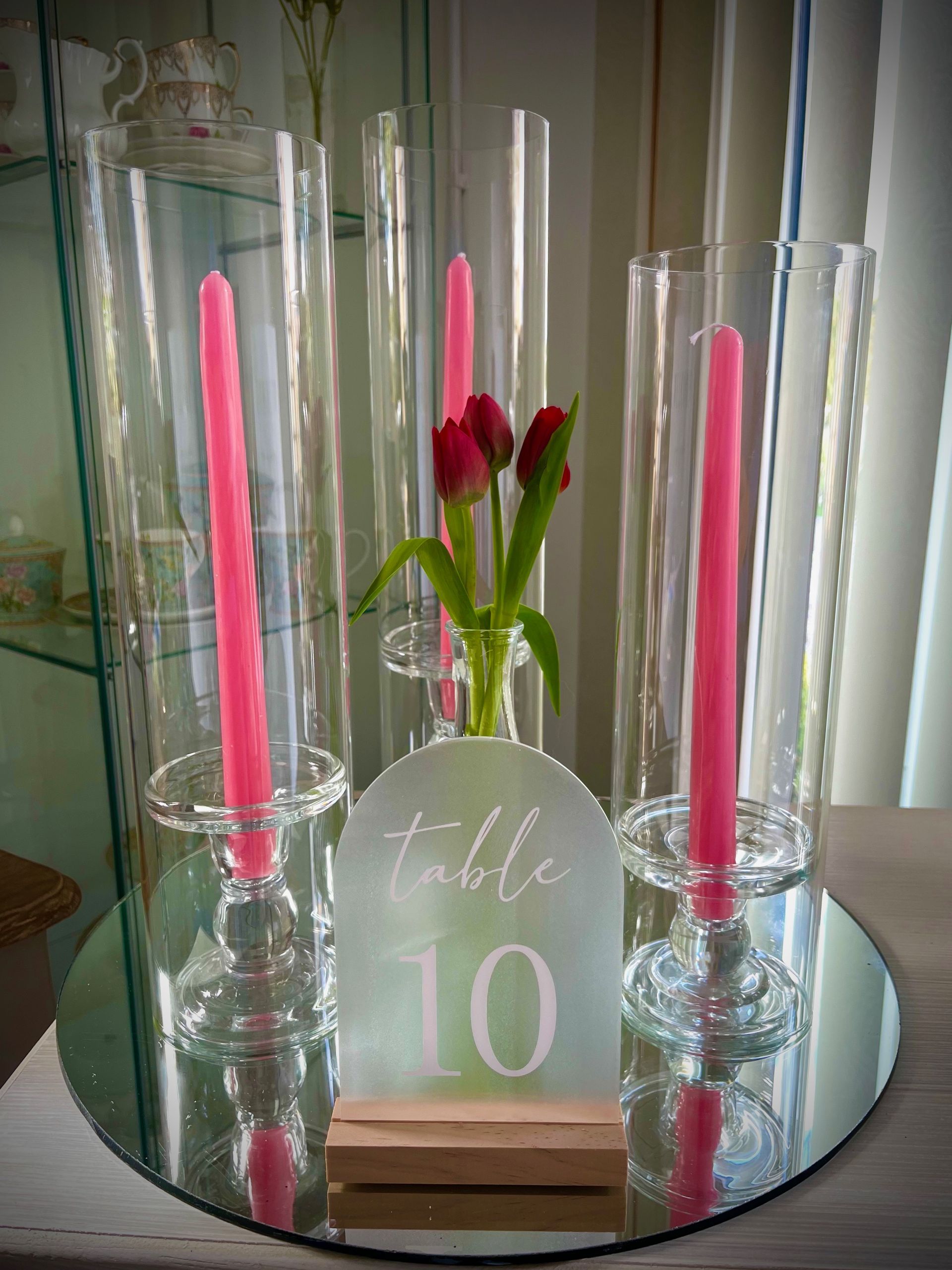 Table centerpiece with pink candles, tulips, and a “table 10” sign on a mirrored tray