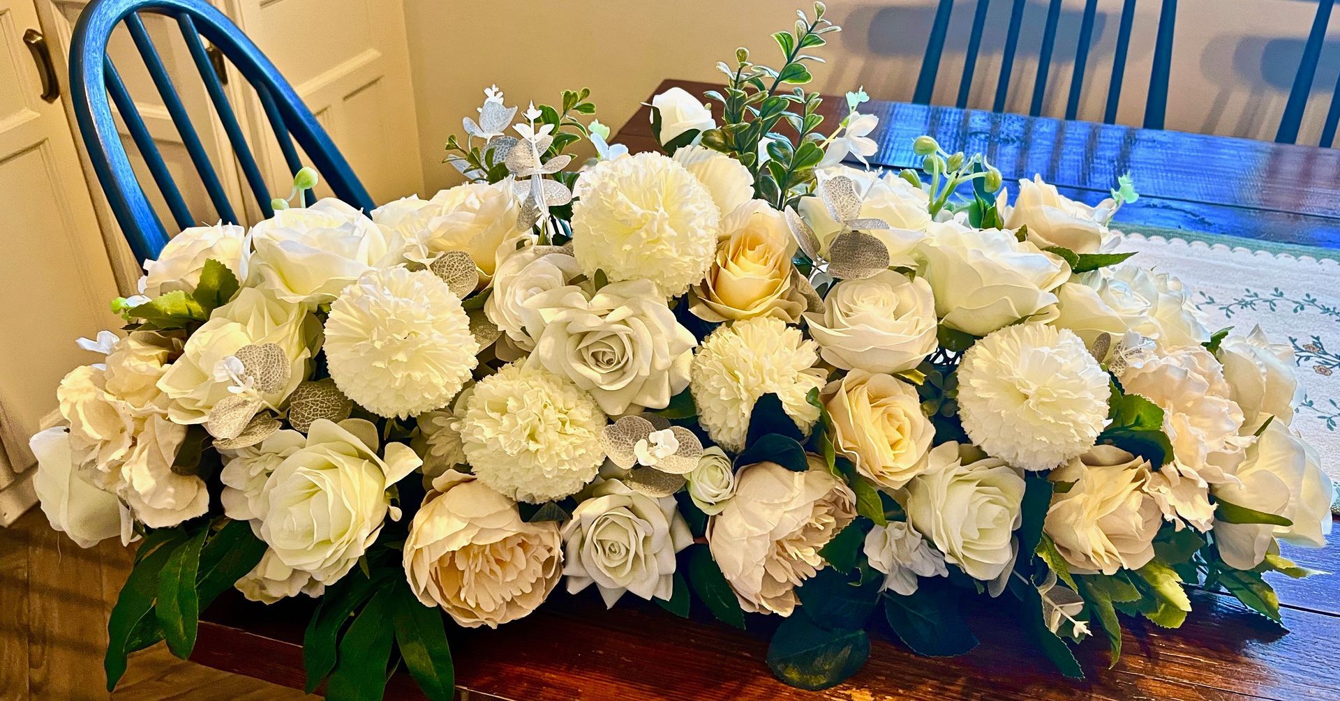 White floral centerpiece with roses and hydrangeas on a dining table