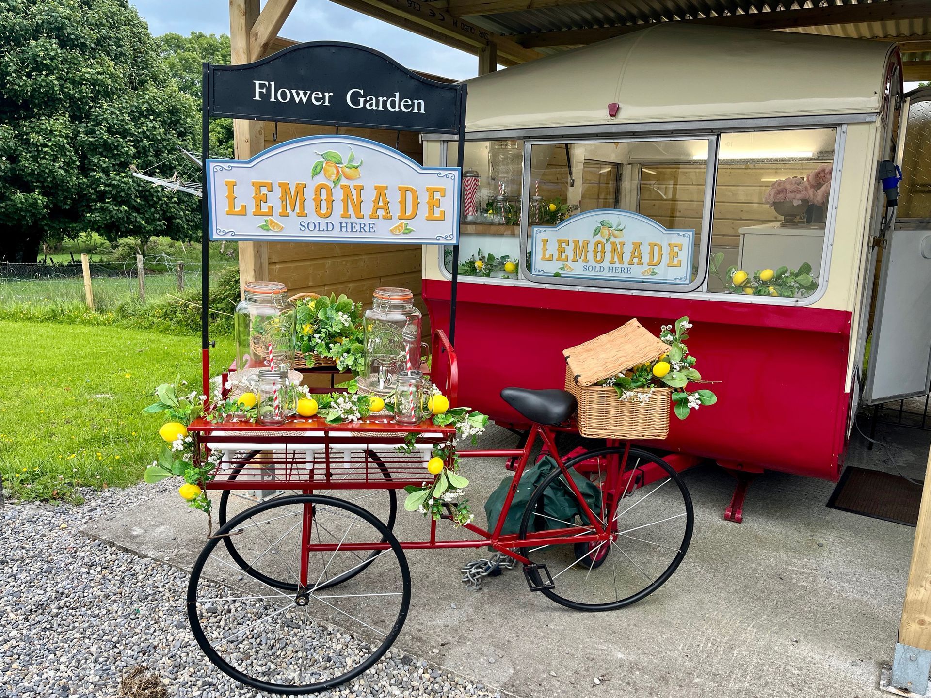 Vintage lemonade cart with red accents and flower decorations at an outdoor stand