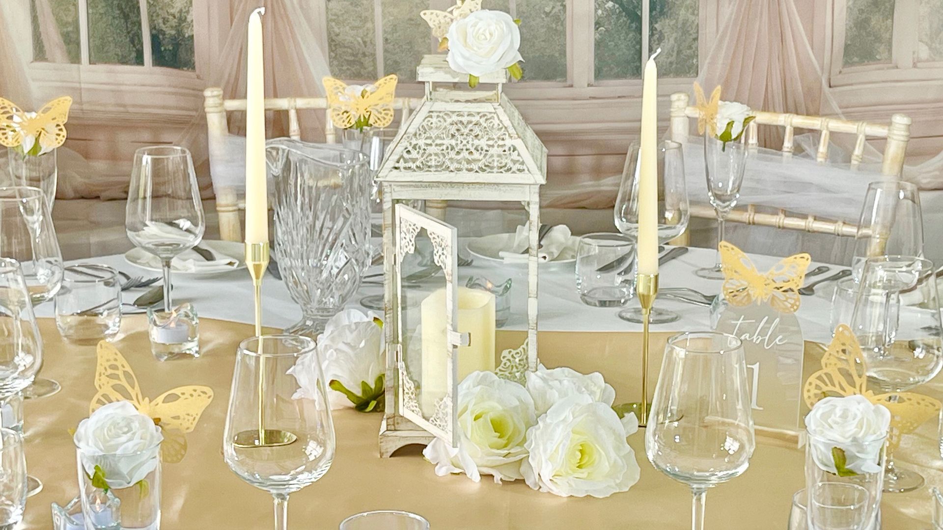 Elegant white and gold wedding table setting with candles, glassware, and floral centerpieces