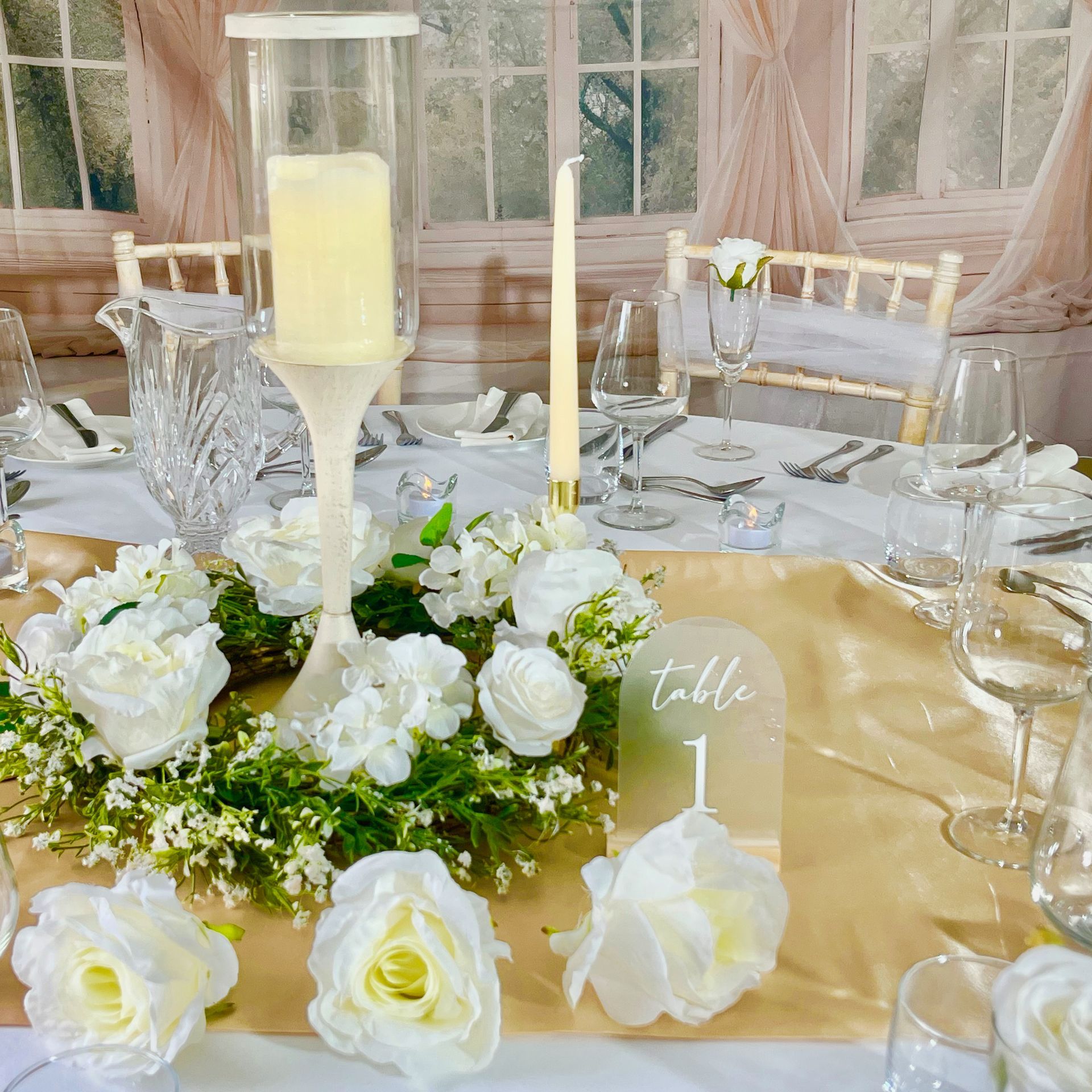Elegant table centerpiece with white flowers, candles, and gold accents in a decorated dining room