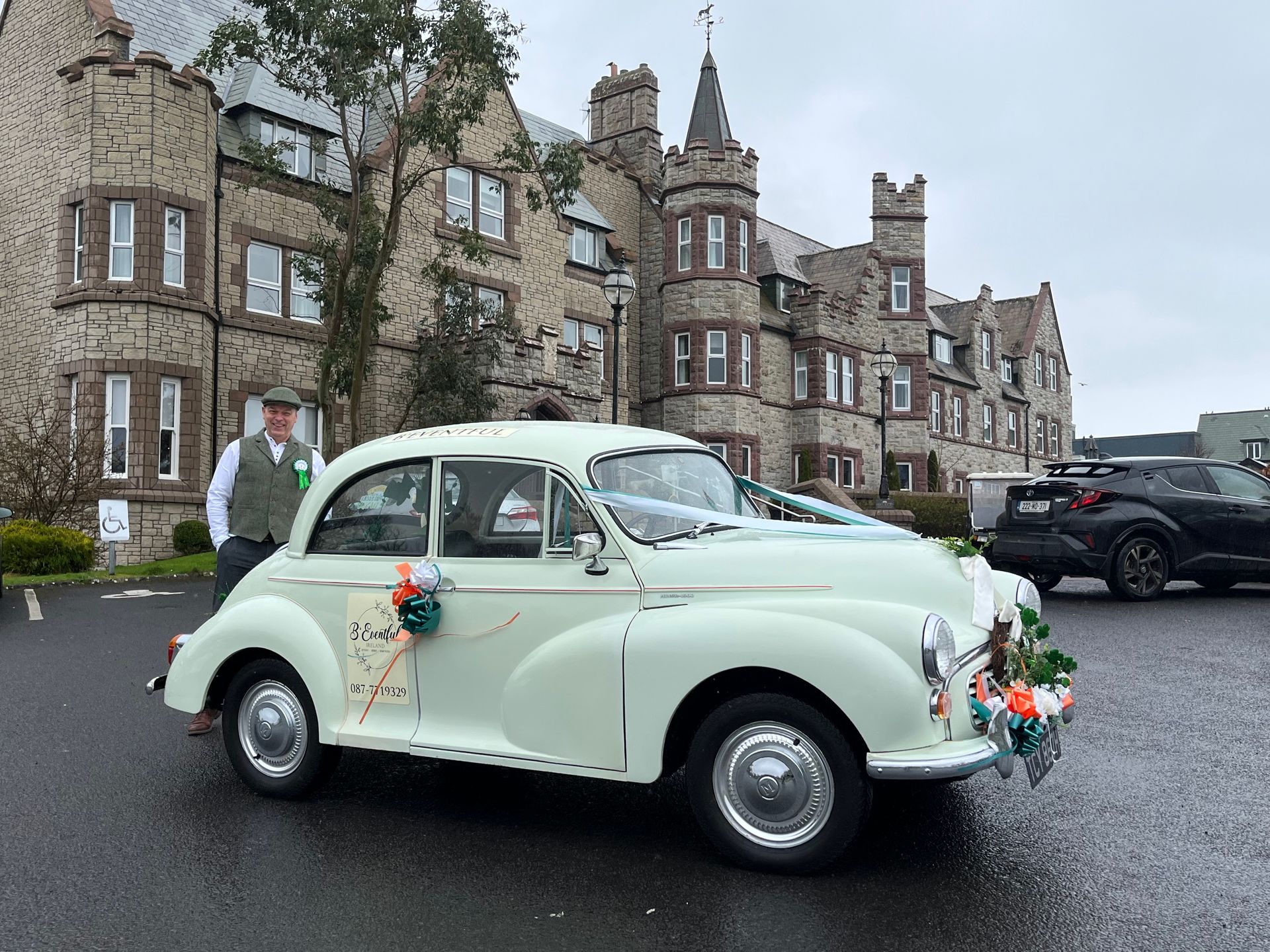 Mint-green vintage car decorated with flowers outside a stone castle-like building