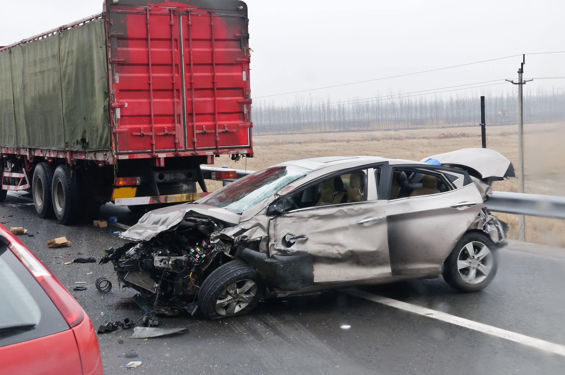A car has crashed into a truck on a highway.