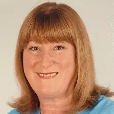 Smiling woman with shoulder-length light brown hair against a plain background