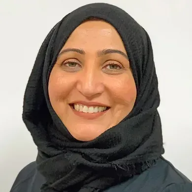 Smiling woman in a black hijab against a light background
