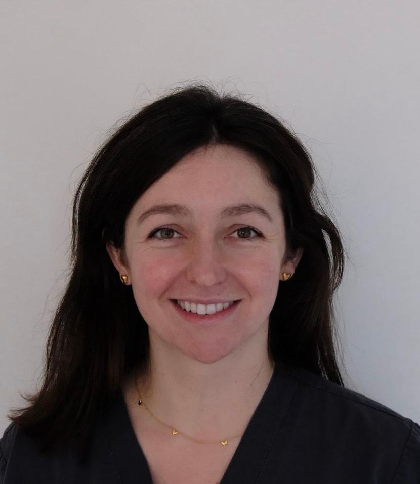 Smiling woman with dark hair against a plain light background