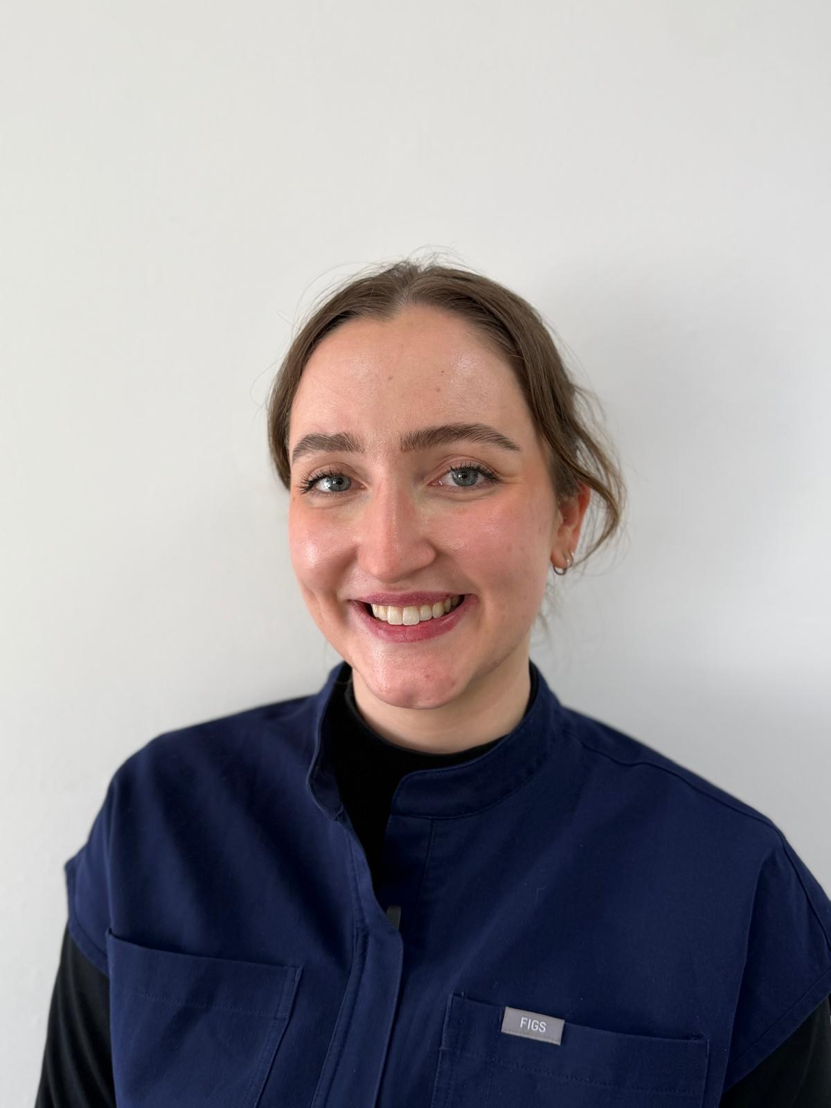 Smiling person in a navy jacket against a plain white background