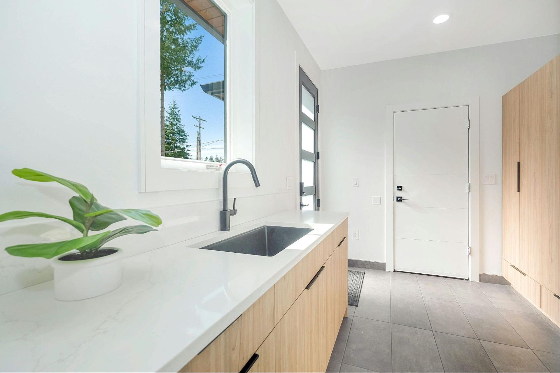 A laundry room with a sink , cabinets , and a window.