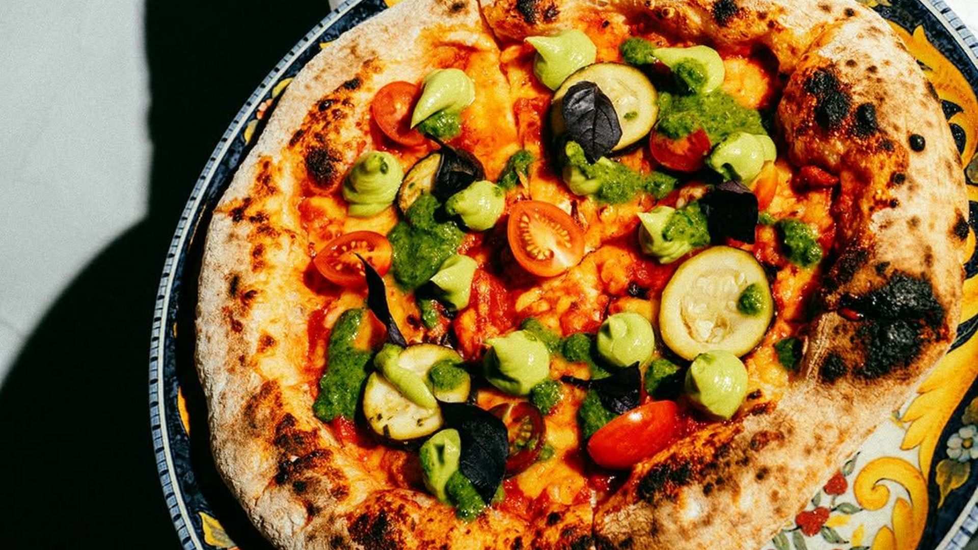 Veggie pizza with olives and green peppers on a black pan