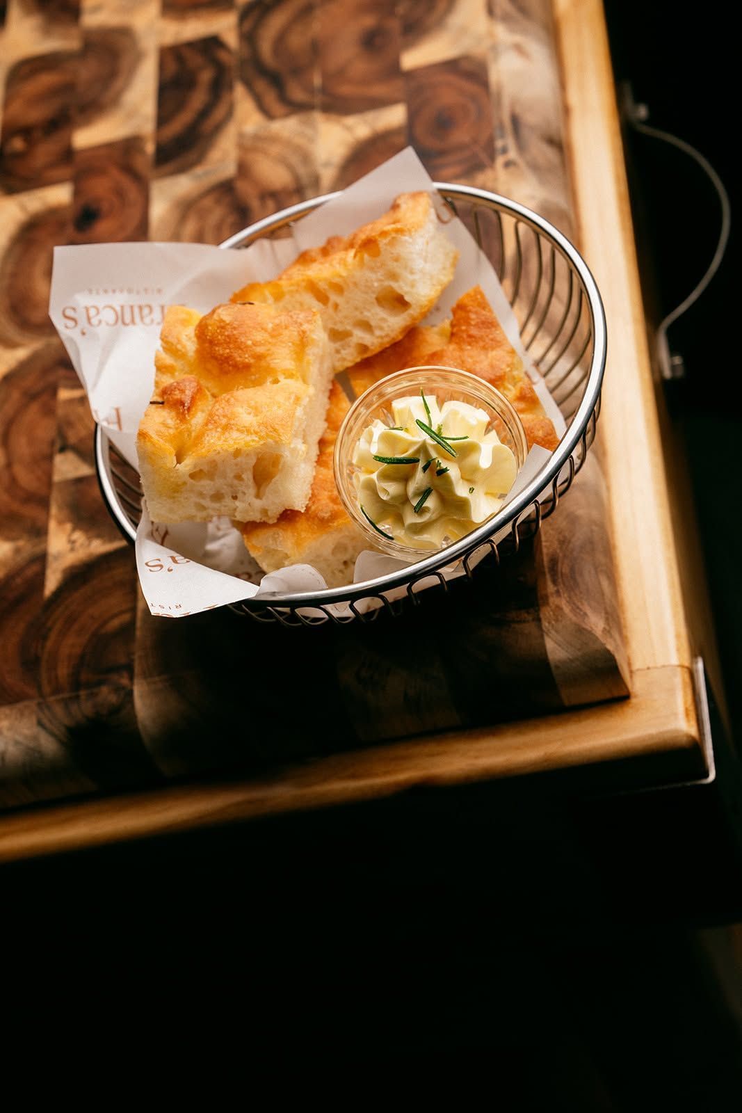 Basket of crispy bread squares with a creamy dip on a wooden serving tray