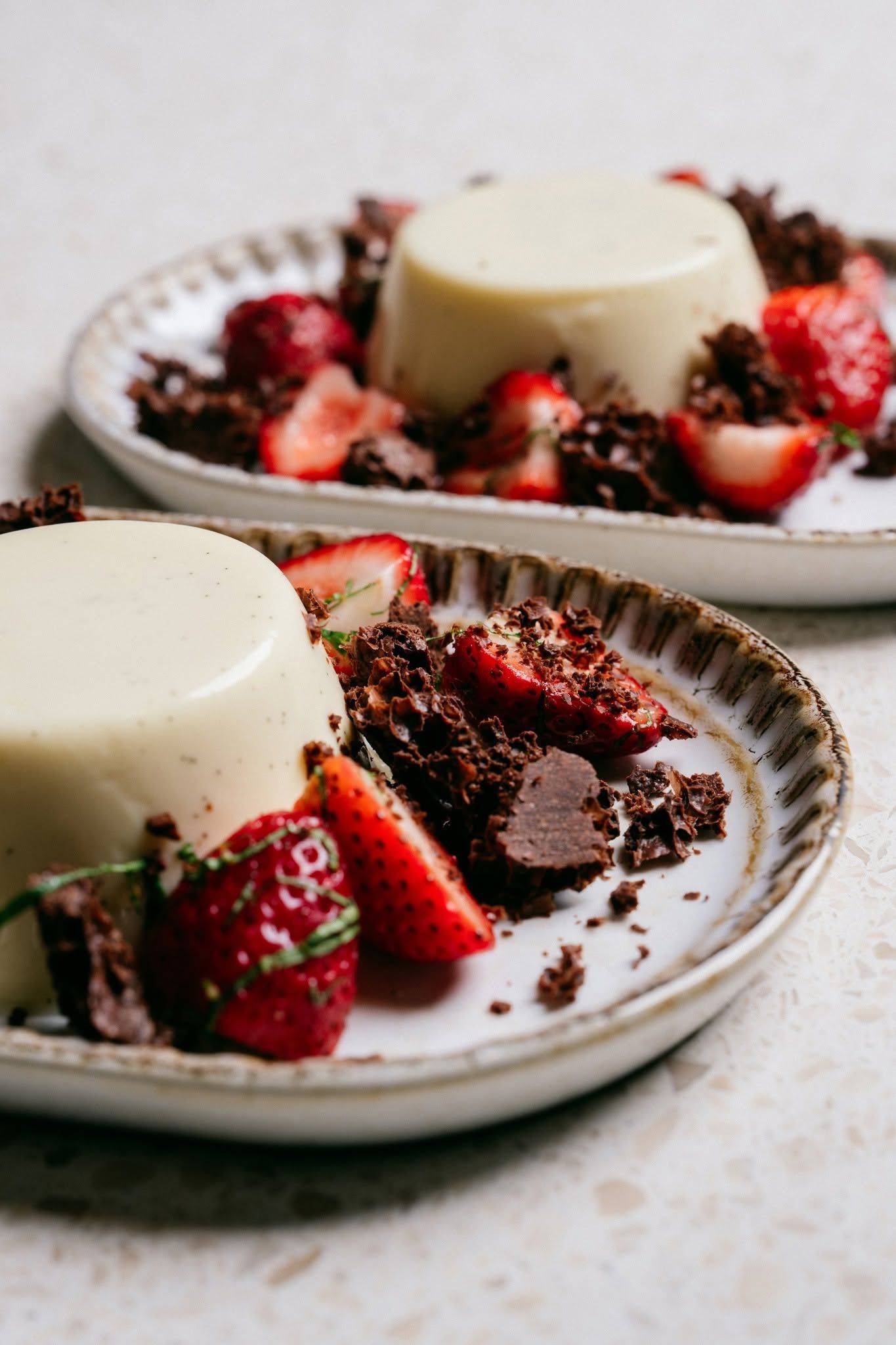 White panna cotta with strawberries and chocolate sauce on white plates