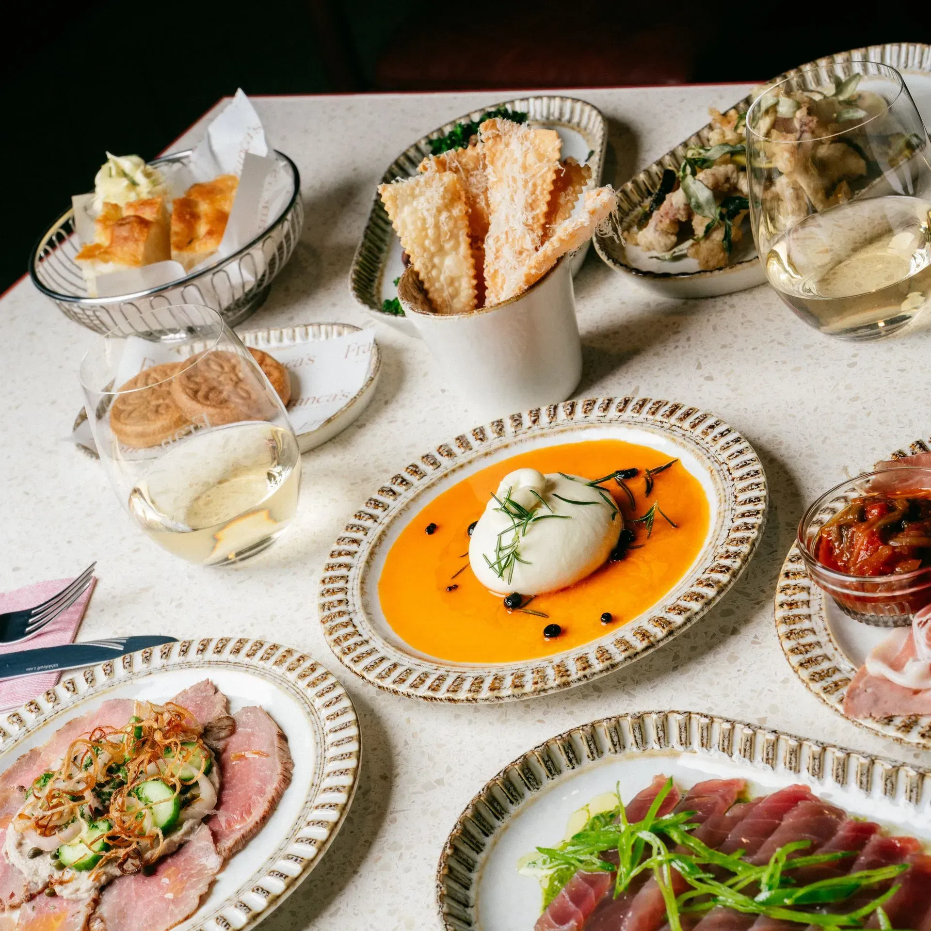 Assorted gourmet appetizers and drinks arranged on a tabletop, including a central plated dish with orange sauce.