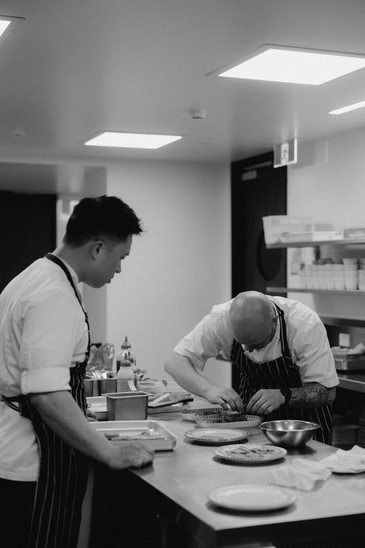 Two people preparing food on a kitchen counter in a bright indoor workspace