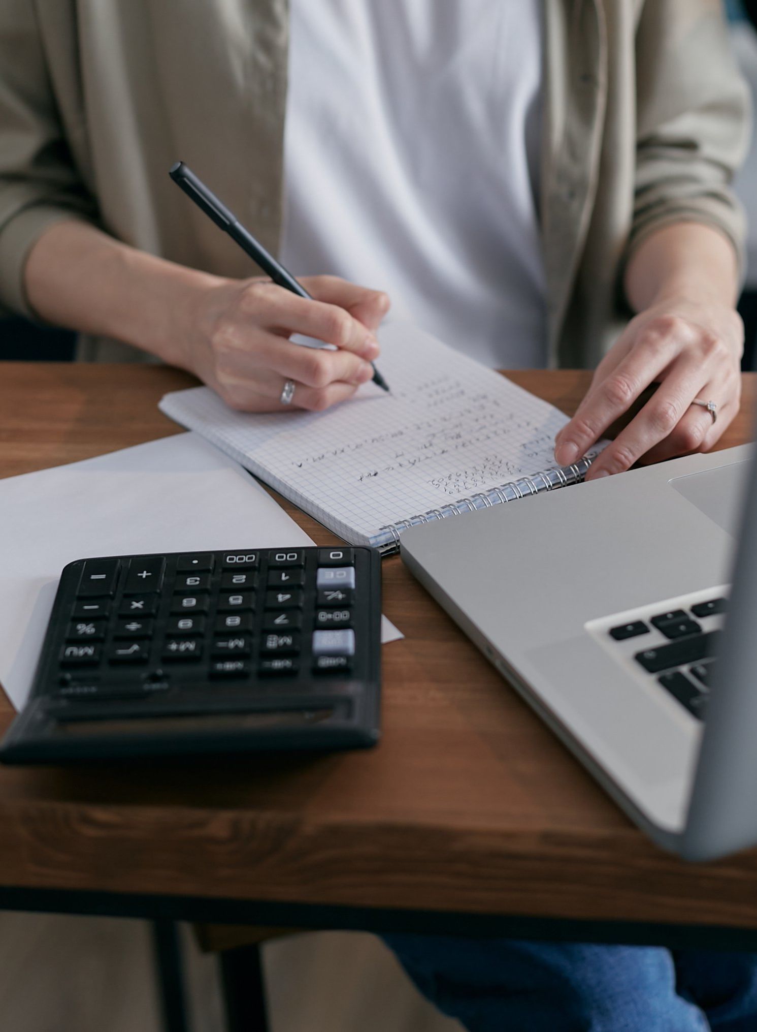 A person is sitting at a desk with a laptop and a calculator.