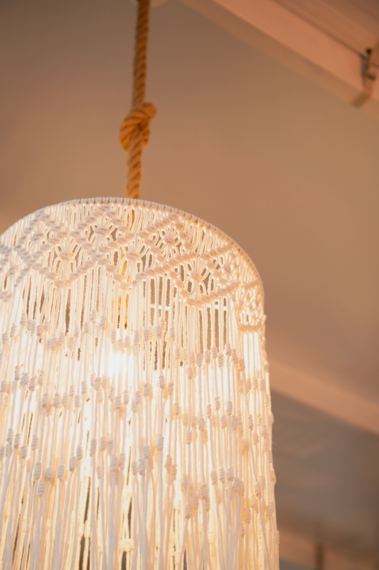 Lampada a sospensione bianca con frange e corda intrecciata appesa al soffitto.