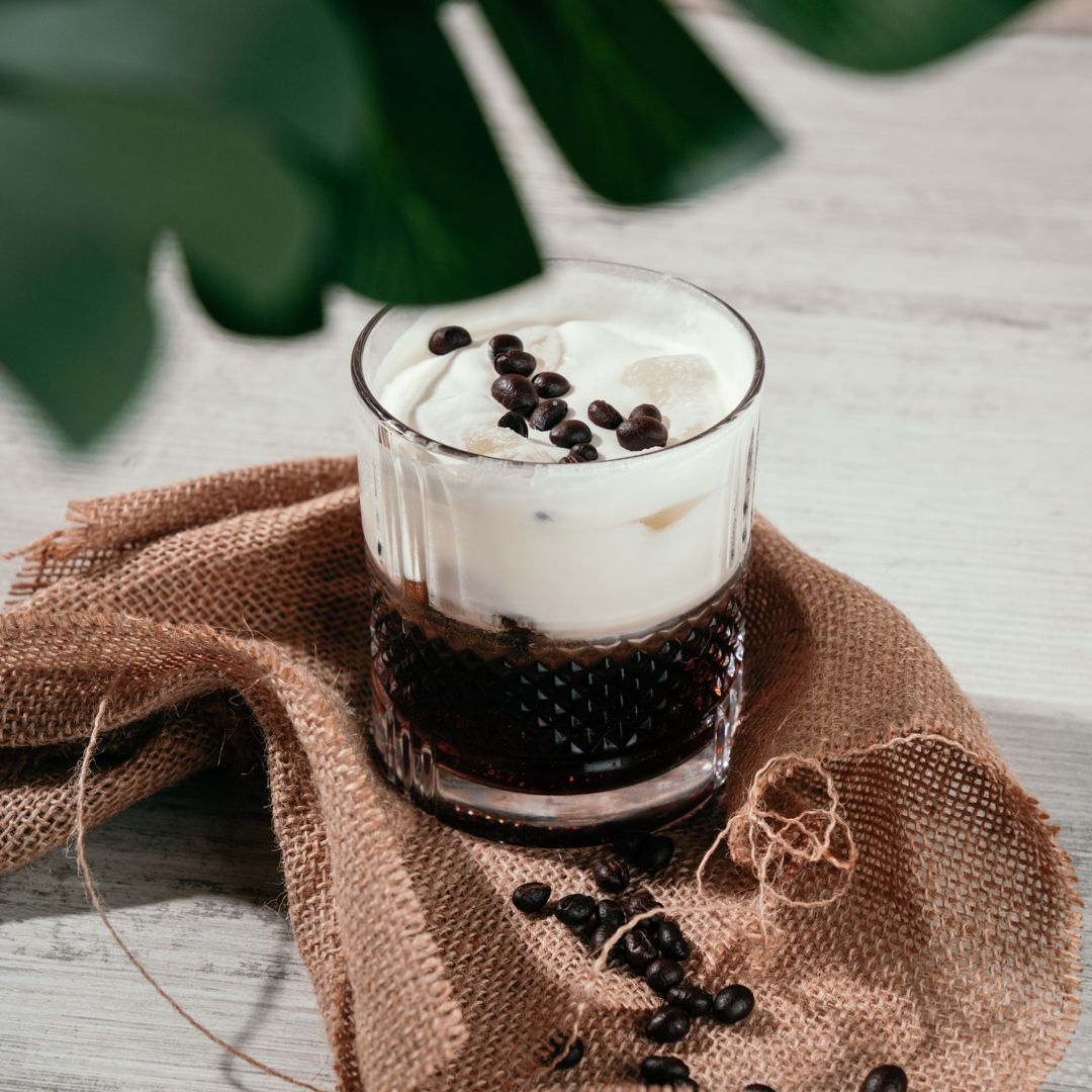 Bicchiere di caffè freddo con panna e chicchi di caffè su un telo di iuta.
