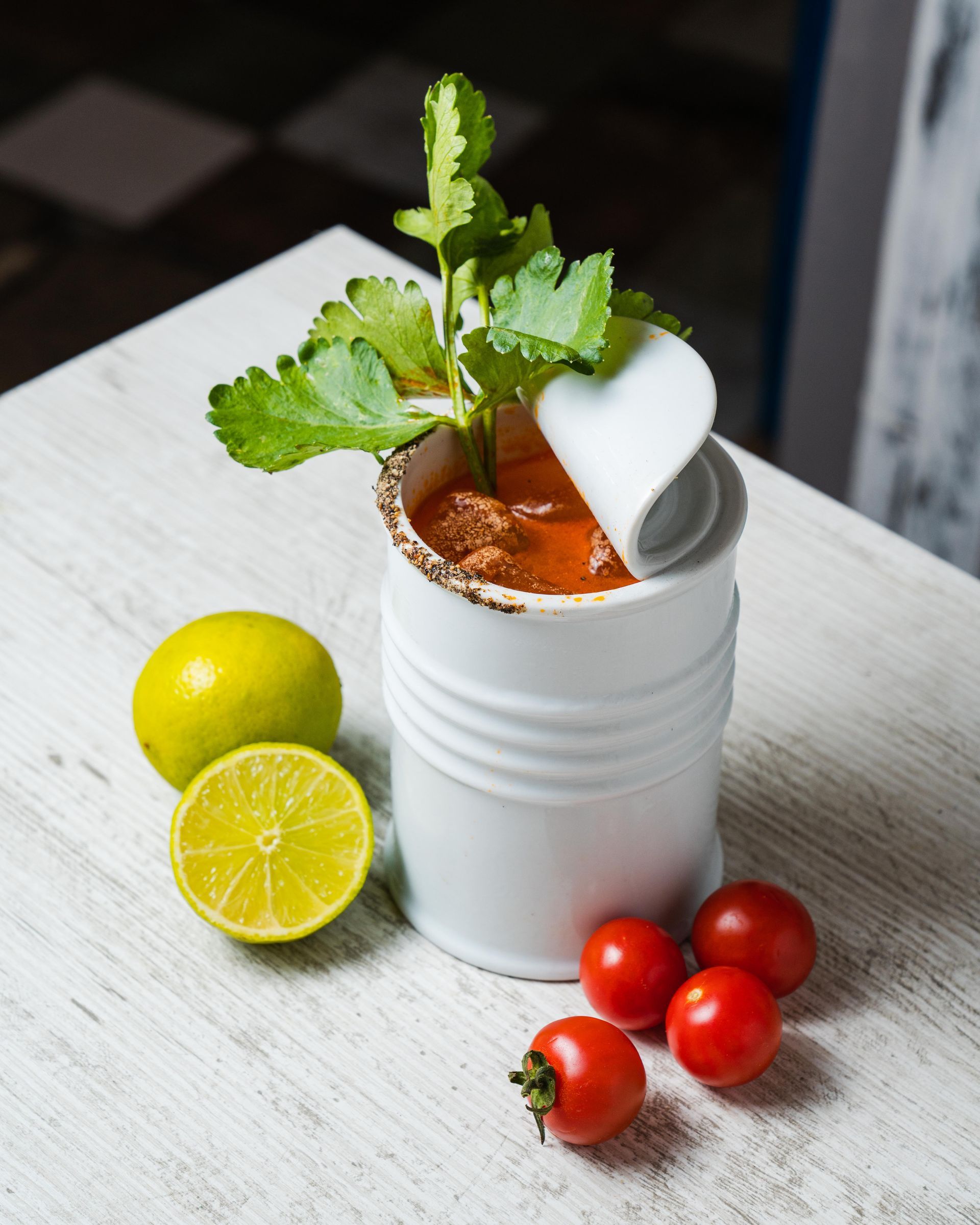 Una bevanda bianca con menta, lime e pomodorini su un tavolo, con un lime tagliato a metà nelle vicinanze.