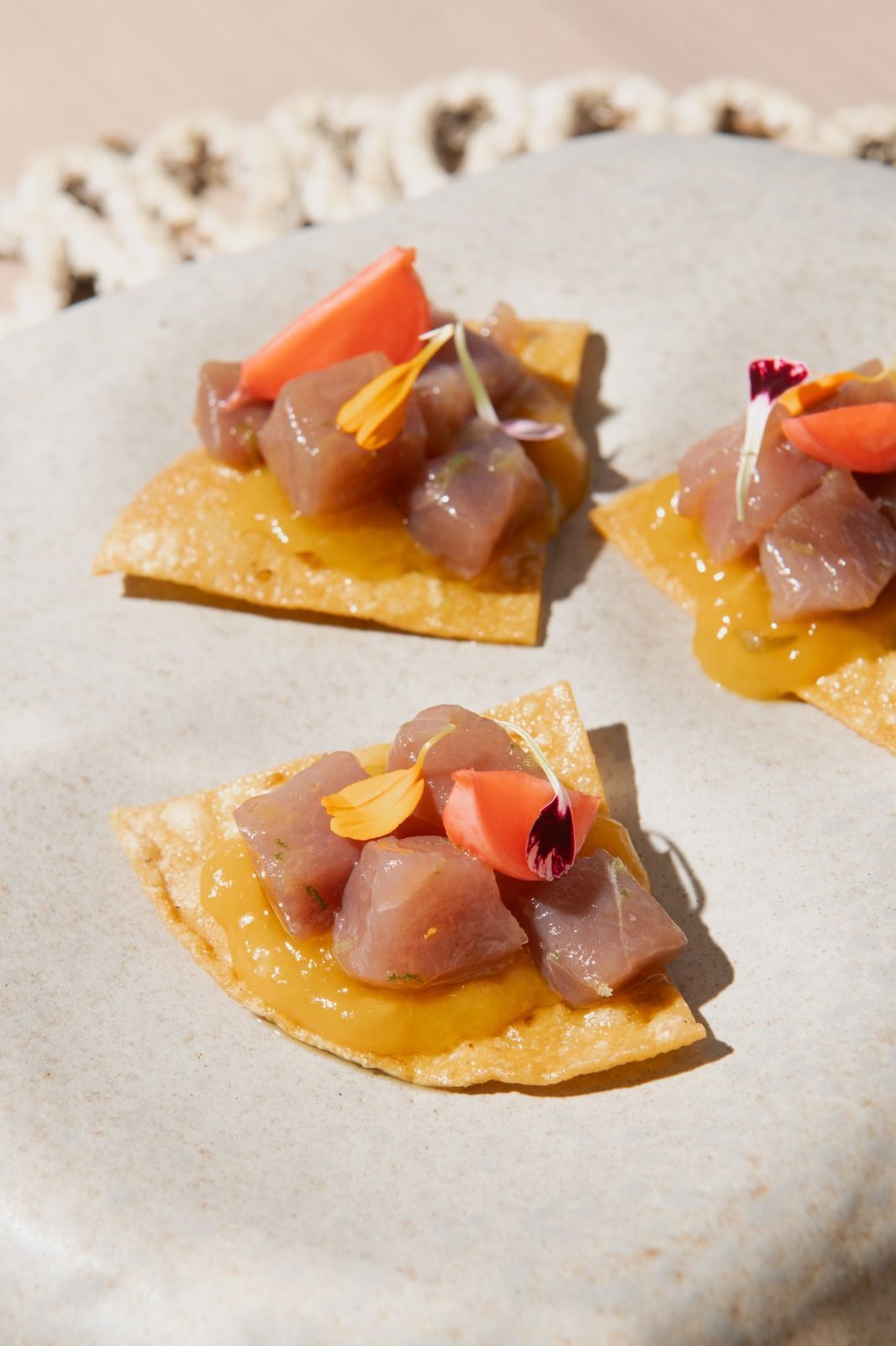Tre tortilla chips con gamberetti, servite su un piatto di pietra con guarnizione all'arancia.