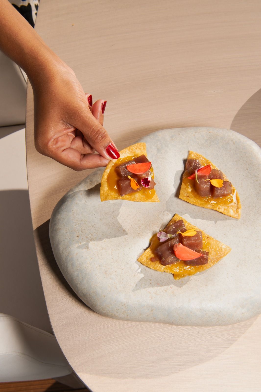 Una mano posiziona una fetta di crostata di frutta su un piatto insieme ad altre due fette su un tavolo