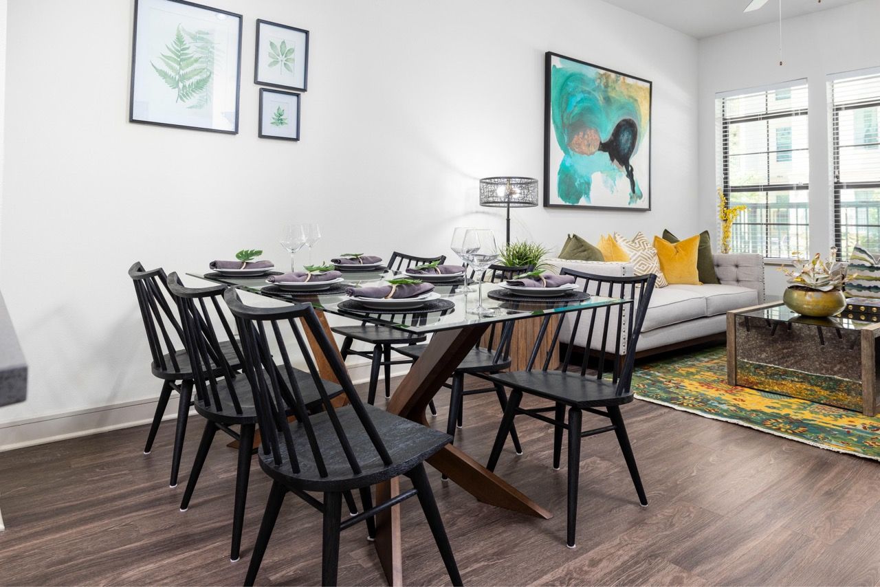 Dining area with glass-top table and black chairs in a modern apartment living space.