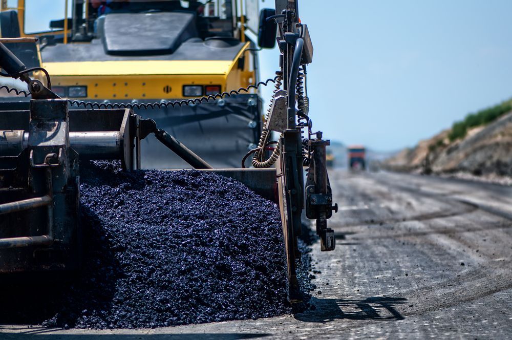 Asphalt Paving Machine Laying Down Fresh Black Asphalt — BC Earthmoving & Civil Construction in East Barron QLD
