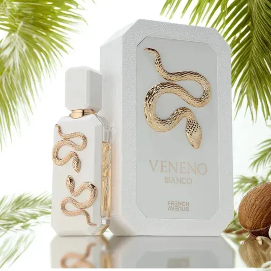 Witte parfumfles en -doos met gouden slangenmotief op een reflecterend oppervlak met palmbladeren.