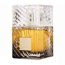 Parfumflesje met een transparante, gedecoreerde dop en goudkleurige vloeistof in een vierkante glazen voet.