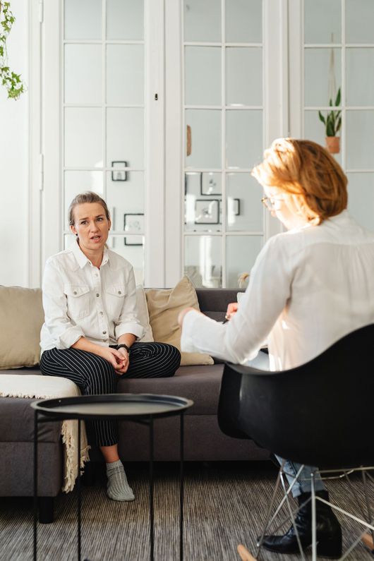 Two people talking in a bright living room with white cabinets and a small round table