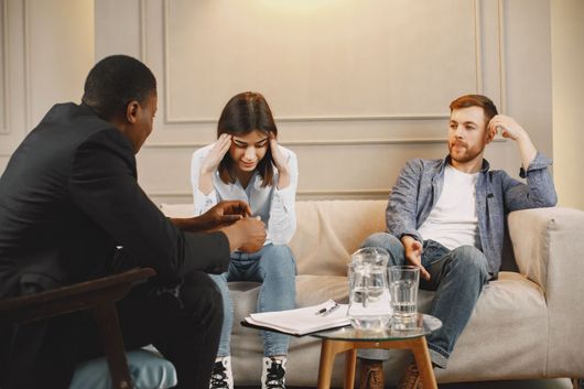 Three people in a meeting room discussing notes around a coffee table
