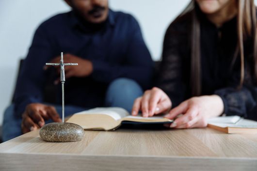 Three people in a meeting room discussing notes around a coffee table