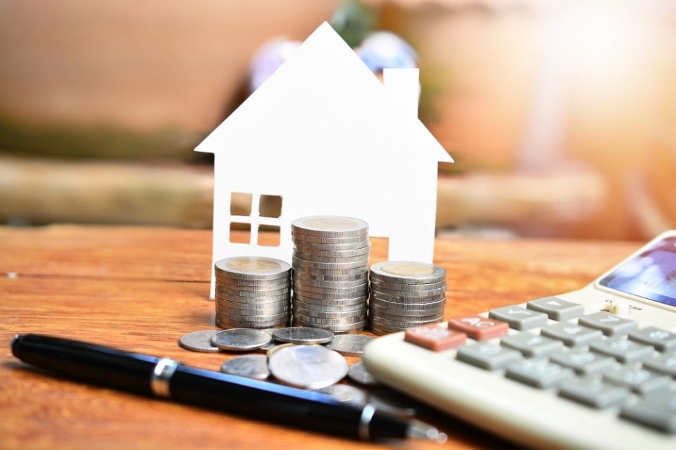 money is lying on the table in front of a small house model