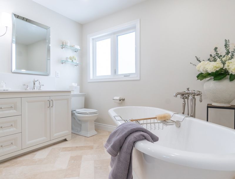 Elegant white bathroom with freestanding tub, vanity, and window.