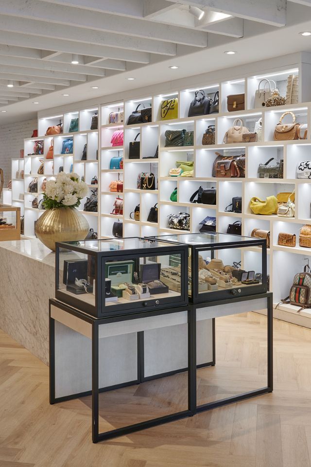 Luxury handbag boutique with white shelves, display cases, and a black-framed glass counter