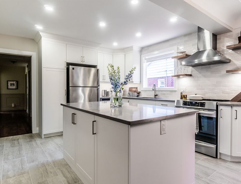 Modern kitchen with white cabinets, island, and stainless steel appliances.