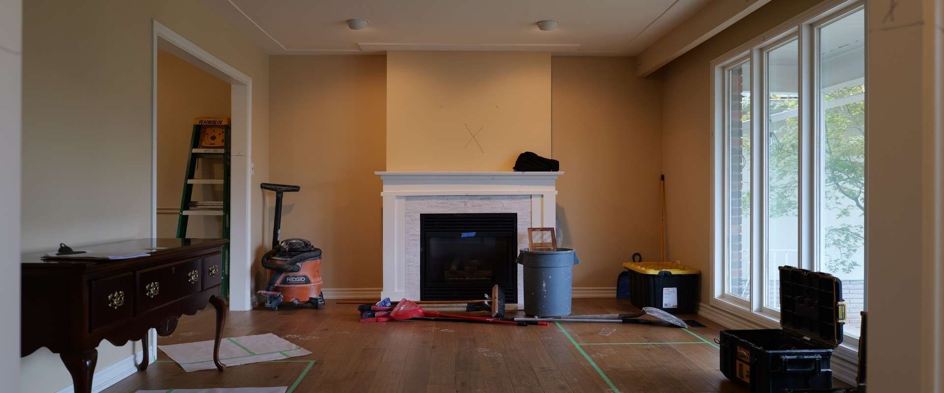 Empty living room with fireplace, chandelier, and sliding glass doors.