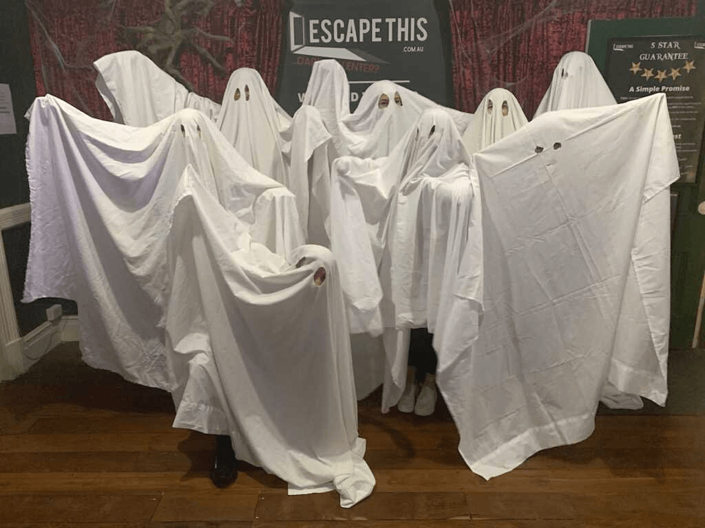 A group of ghosts are standing next to each other covered in white sheets.