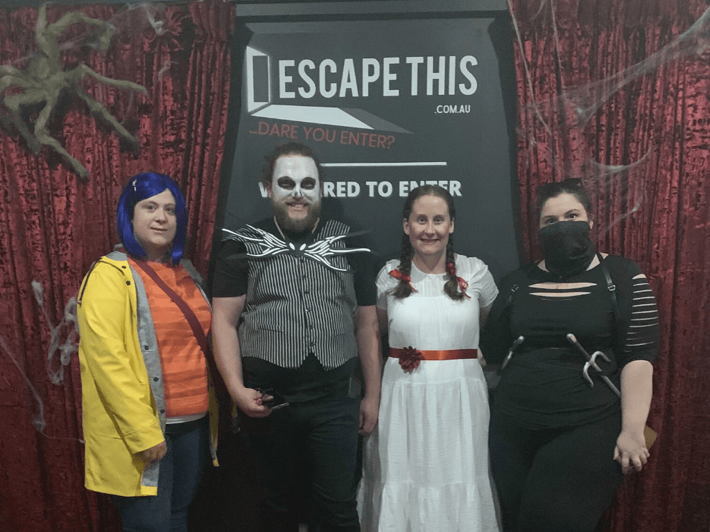 A group of people are posing for a picture in front of a sign that says escape this.