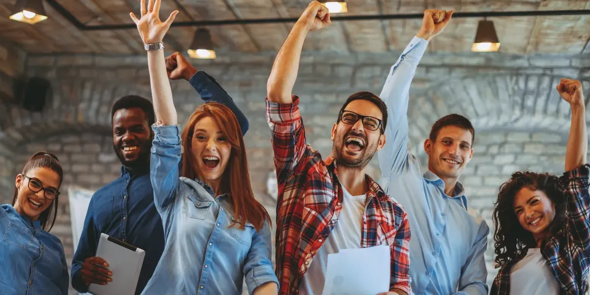 A group of coworkers standing next to each other celebrating and smiling.