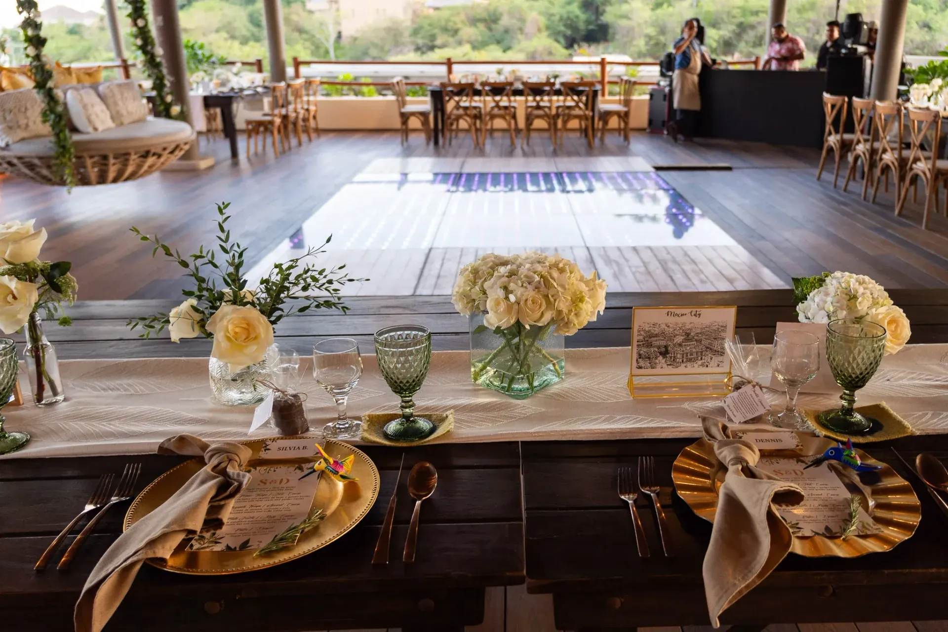 Montaje de mesas para la recepción de boda con centros de mesa florales y pista de baile.
