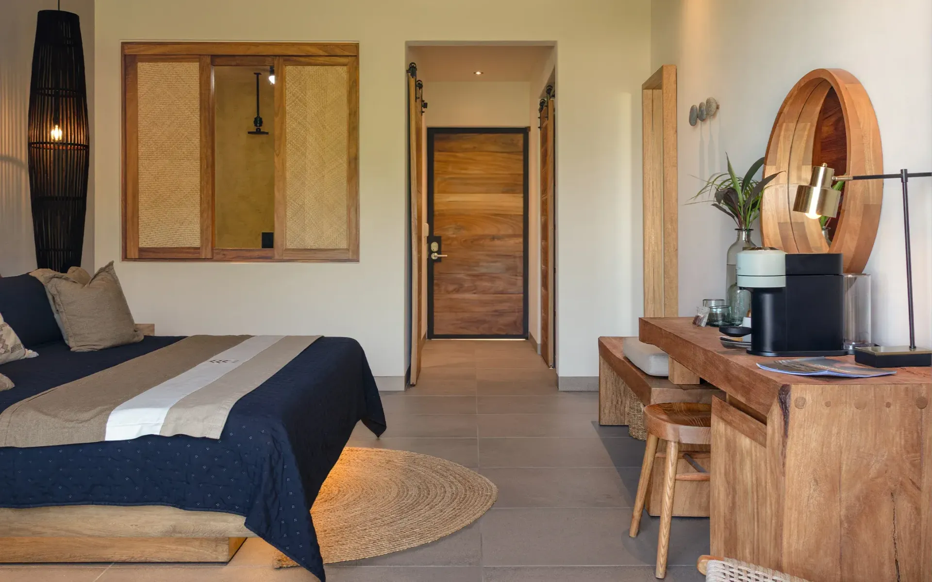 Dormitorio con muebles de madera, cama con sábanas azules y beige y una alfombra redonda tejida.