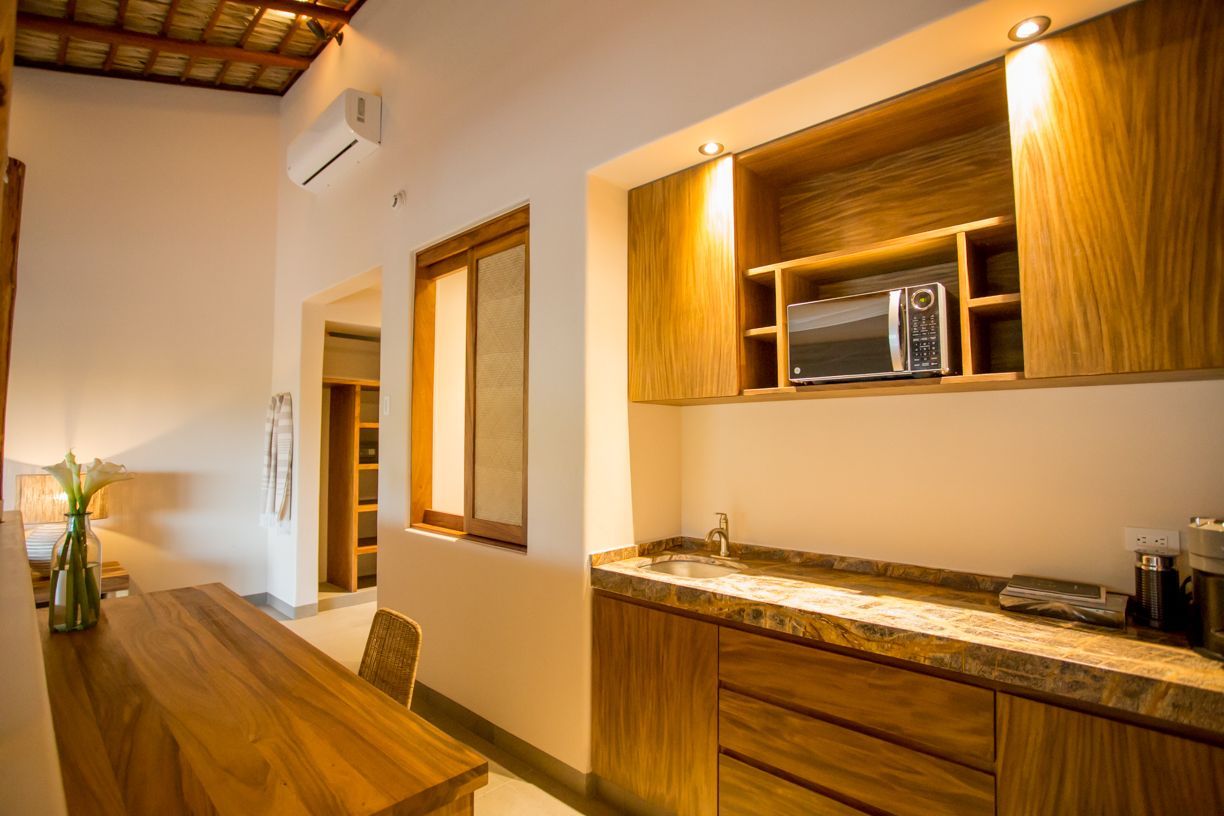 Cocina interior con armarios de madera, encimera y microondas. También dispone de mesa de comedor y ventana.