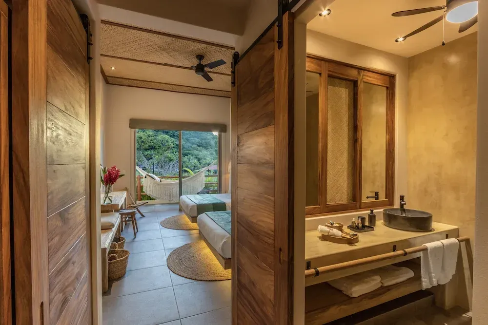 Conjunto de baño y dormitorio con puertas de madera, tocador y dos camillas de masaje.