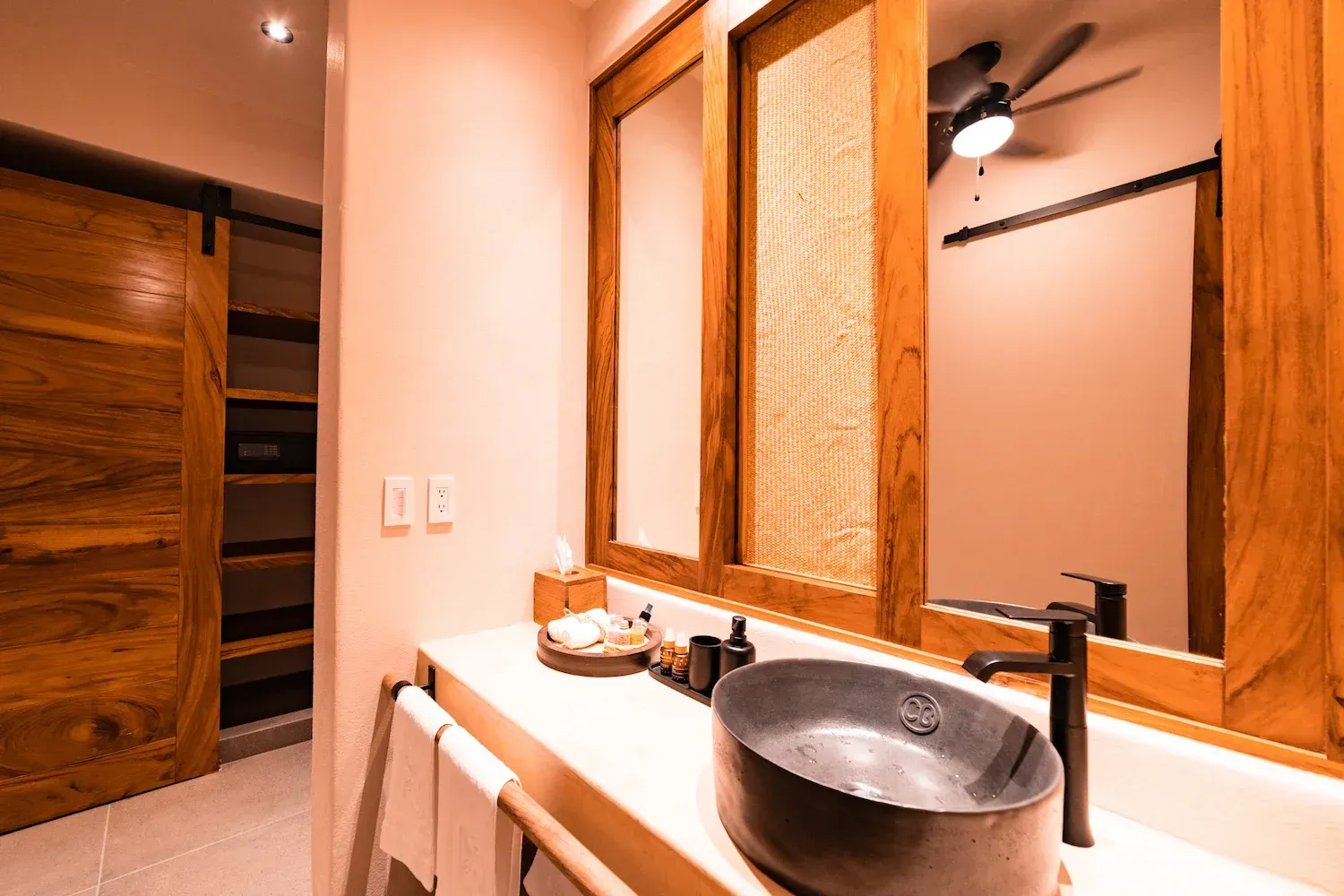 Baño con detalles de madera, lavabo sobre encimera y un gran espejo.