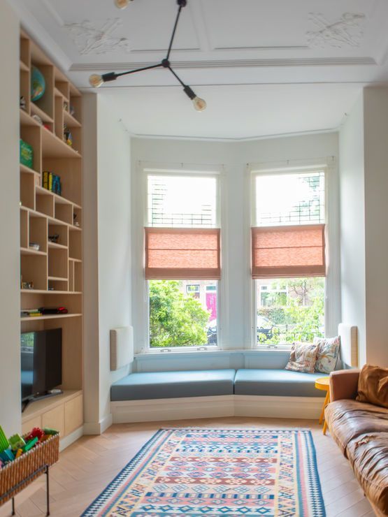 Woonkamer met ingebouwde boekenkasten, erker met zitgelegenheid, vloerkleed en moderne lamp.